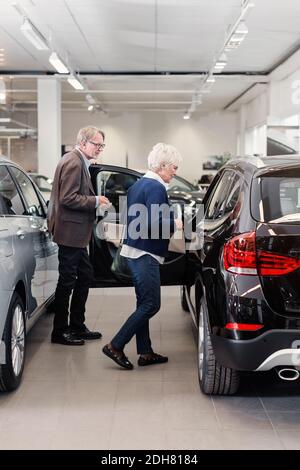 Un couple senior examine la voiture en magasin Banque D'Images