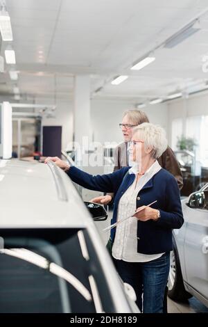 Un couple senior examine la voiture dans la salle d'exposition Banque D'Images
