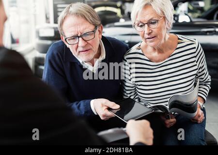 Couple senior qui cherche un accord dans un concessionnaire automobile Banque D'Images