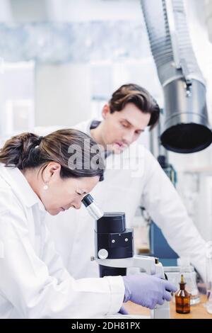 Scientifique féminin utilisant un microscope en laboratoire Banque D'Images