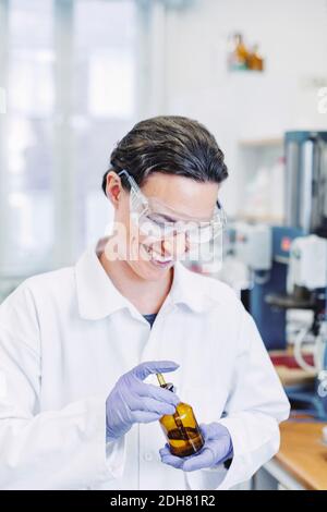 Bonne scientifique féminine utilisant une pipette lors de l'examen de produits chimiques en laboratoire Banque D'Images