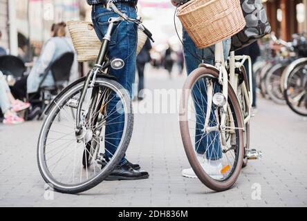 Partie basse du couple senior debout avec des vélos dans la rue Banque D'Images