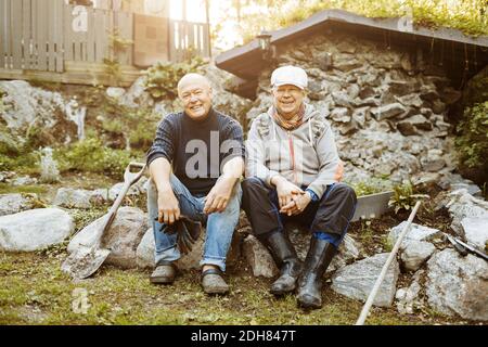 Portrait d'un couple gay heureux assis sur des rochers au jardin Banque D'Images
