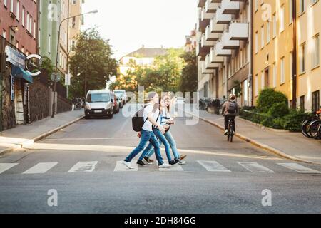 Vue latérale sur les adolescents traversant la route en ville Banque D'Images