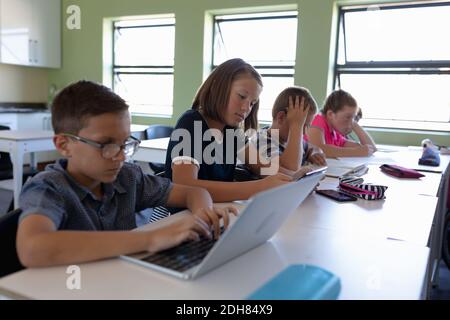 Groupe d'écoliers assis à un bureau dans une salle de classe de l'école primaire Banque D'Images