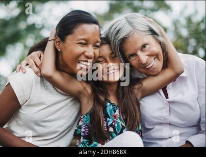 Portrait d'une fille heureuse embrassant mère et grand-mère à la cour Banque D'Images