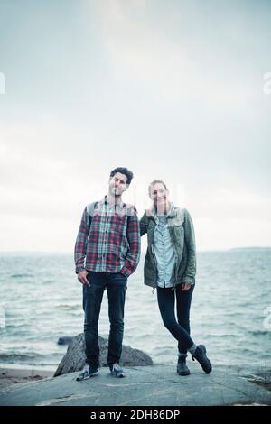 Portrait complet d'un couple de merveilleux confiants debout sur le rocher par mer Banque D'Images