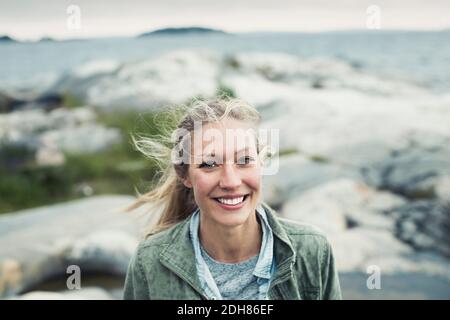 Portrait de la jeune femme heureuse sur le rocher par la mer Banque D'Images