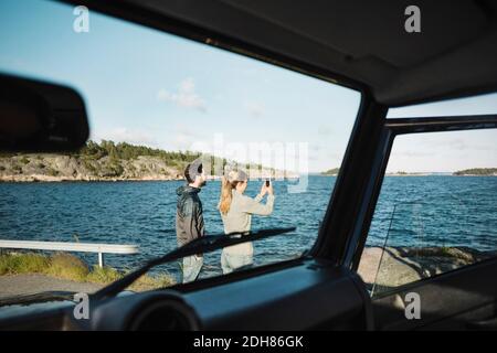 Couple vu à travers le pare-brise de voiture au bord du lac Banque D'Images