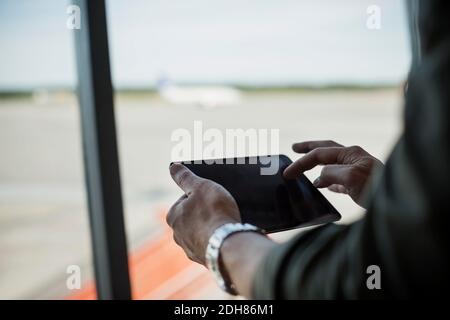 Image rognée d'un homme d'affaires à l'aide d'une tablette numérique à l'aéroport Banque D'Images