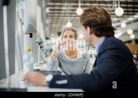 Bonne femme d'affaires parlant à un collègue au café de l'aéroport Banque D'Images