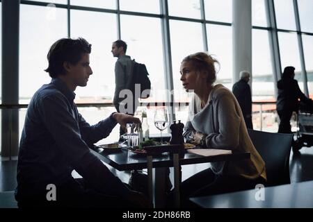 Les gens d'affaires parlent tout en mangeait au café de l'aéroport Banque D'Images