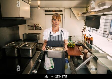 Portrait d'un chef confiant tenant un contenant avec des aliments dans un camion Banque D'Images