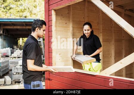 Les étudiants en charpenterie transportant des planches tout en travaillant à l'extérieur Banque D'Images