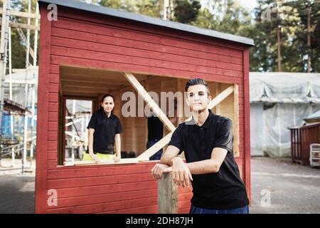 Portrait d'un étudiant en menuiserie confiant pendu sur une planche avec un étudiant en arrière-plan Banque D'Images