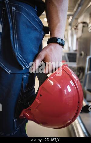 Mi-section d'un professeur de mécanicien d'automobiles tenant un casque Red Hardhat à l'atelier Banque D'Images