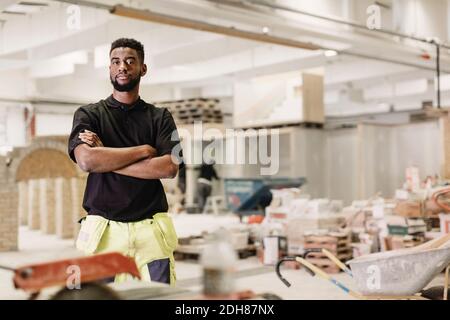 Portrait d'un homme confiant étudiant en charpenterie debout bras croisés atelier Banque D'Images