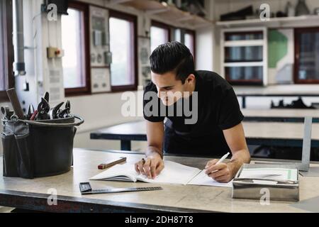 Un jeune étudiant du secondaire écrit en livre à l'atelier Banque D'Images