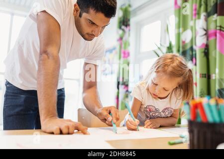 Les enfants de sexe masculin aident la petite fille à dessiner en classe Banque D'Images