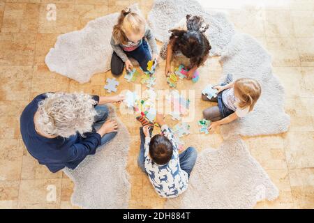 Vue en grand angle de l'enseignant et des enfants jouant au puzzle Banque D'Images