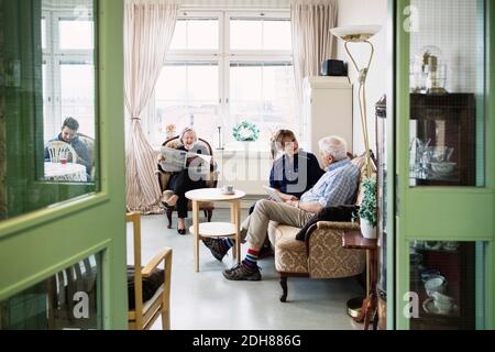 Gardiens avec un couple senior assis dans la salle de séjour à l'infirmière accueil Banque D'Images