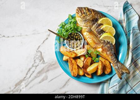 dorade grillée, orata, poisson dorado servi sur une assiette avec des pommes de terre rôties et de la moutarde, vue horizontale d'en haut, plat Banque D'Images