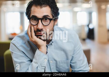 Portrait d'un homme avec la main sur le menton assis dans le couloir Banque D'Images