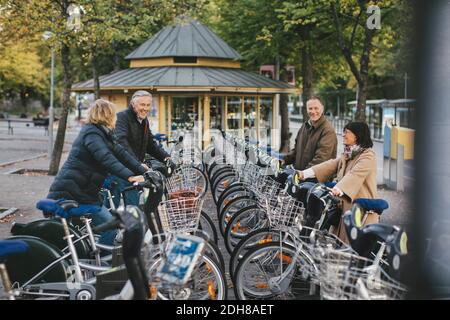Deux couples âgés qui prennent des vélos de location sur le parking Banque D'Images