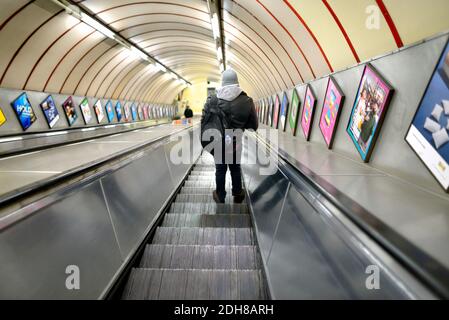 Londres, Angleterre, Royaume-Uni. Homme sur un escalier roulant dans une station de métro Banque D'Images