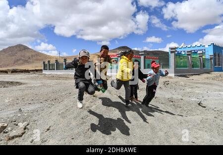 (201210) -- LHASSA, le 10 décembre 2020 (Xinhua) -- les enfants jouent près d'une école maternelle nouvellement construite dans le canton de Pumaqangtang, dans le comté de Nagarze, à Shannan, dans le sud-ouest de la Chine, région autonome du Tibet, le 16 avril 2020. Pumaqangtang, la ville la plus haute de Chine, a une altitude moyenne de 5,373 mètres, avec des niveaux d'oxygène inférieurs à 40 pour cent de celui au niveau de la mer. Ici, les villageois vivaient dans des maisons en roche de terre sans électricité, eau courante, légumes ou fruits disponibles. Ces conditions de vie difficiles se sont poursuivies jusqu'aux années 1970. Aujourd'hui, tous les villageois de Pumaqangtang ont déménagé dans de meilleures résidences Banque D'Images