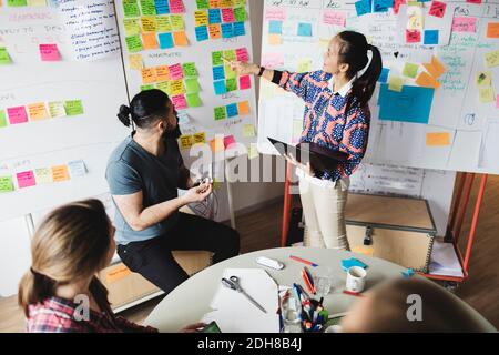 Vue en grand angle d'une femme d'affaires montrant des notes et expliquant ses collègues pendant la réunion Banque D'Images