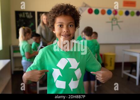 L'écolier porte un t-shirt vert avec un logo de recyclage blanc Banque D'Images