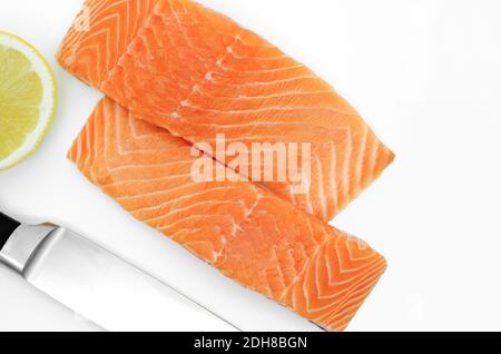 Deux tranches de filet de saumon frais, vue de dessus sur fond blanc. Couteau et citron Banque D'Images