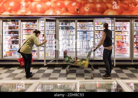 Couple choisissant à la section réfrigérée dans le supermarché Banque D'Images