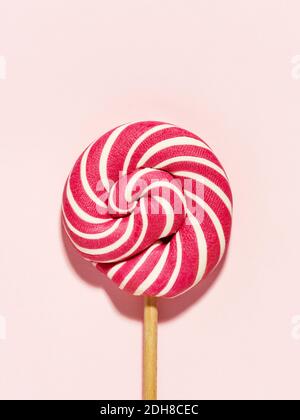 Bonbon Lollipop blanc et rouge vif sur fond rose. Pose à plat, minimale. Concept anniversaire. Banque D'Images