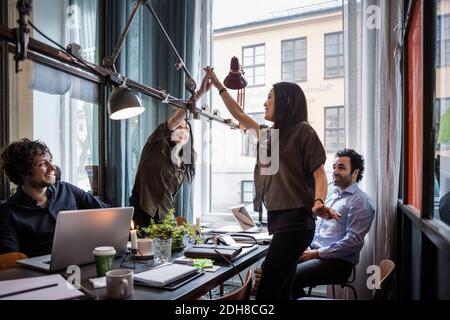 Les collègues féminins donnent cinq personnes de haut lorsqu'ils sont debout à table pendant la réunion Banque D'Images