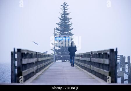 Boltenhagen, Allemagne. 10 décembre 2020. Un homme marche en face de vous à travers la jetée sur la côte de la mer Baltique. En raison du verrouillage partiel de la couronne, les hôtels, les restaurants et les installations touristiques sur la côte de la mer Baltique dans le Mecklembourg-Poméranie-Occidentale sont fermés. Credit: Jens Büttner/dpa-Zentralbild/dpa/Alay Live News Banque D'Images