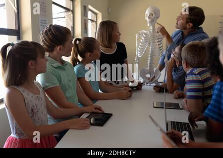 Professeur de sexe masculin utilisant un modèle de squelette humain à enseigner Banque D'Images