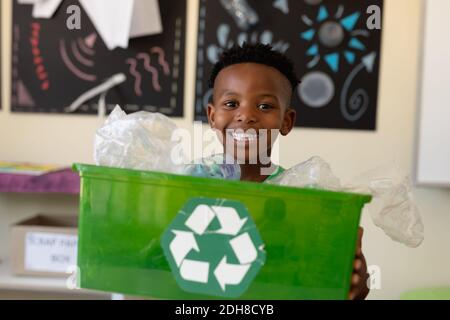 Écolier tenant une caisse verte avec un logo de recyclage blanc dessus Banque D'Images