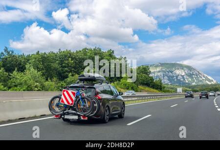 Voiture noire avec coffre à bagages de toit et porte-vélos de coffre roulant sur l'autoroute. Magnifique paysage de montagne Banque D'Images