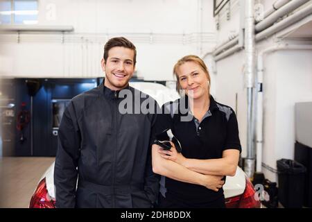 Portrait d'un mécanicien heureux debout avec une femme en réparation automatique boutique Banque D'Images