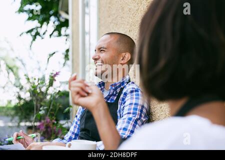 Homme souriant avec une collègue assise à l'extérieur du café Banque D'Images