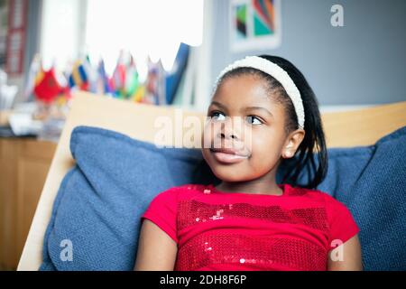 Gros plan d'une jeune fille souriante qui se repose sur une chaise en classe Banque D'Images