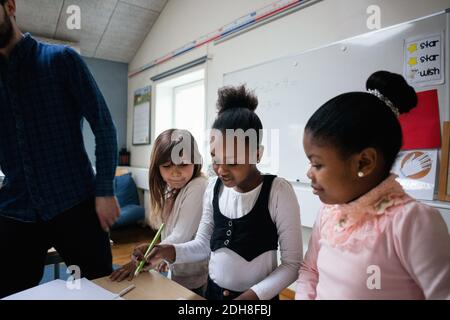 Les étudiantes écrivent sur papier pendant que l'enseignante est en classe Banque D'Images