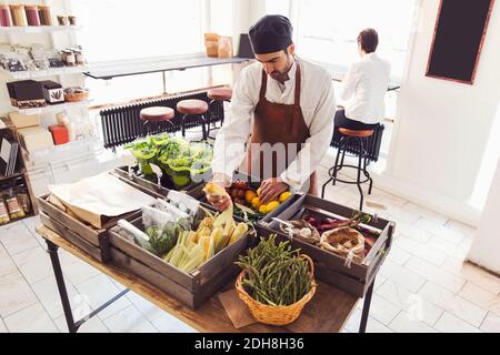 Vue en grand angle du propriétaire qui organise des légumes à l'épicerie stocker Banque D'Images