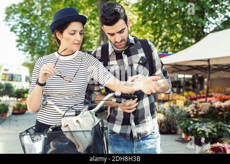 Homme lisant le tatouage sur la main de la femme tout en se tenant par la fleur boutique Banque D'Images