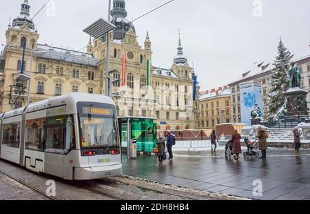 Graz, Autriche-03 décembre 2020: Personnes dans la station de tram à la place principale Hauptplatz, bâtiment de l'hôtel de ville en arrière-plan, portant des masques de visage pendant le cor Banque D'Images