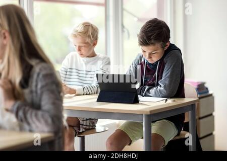 Les écoliers apprennent en ligne à partir d'une tablette numérique en classe Banque D'Images