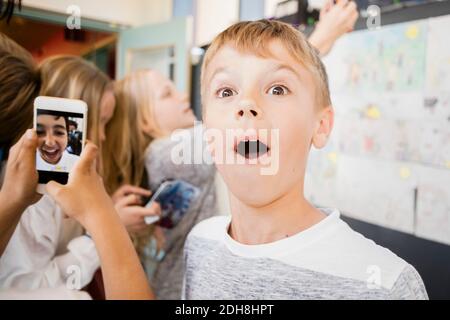 Un garçon surpris debout au milieu d'amis prenant le selfie dans le couloir Banque D'Images