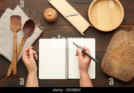 Ordinateur portable ouvert avec draps blancs vierges et ustensiles de cuisine une table en bois marron Banque D'Images